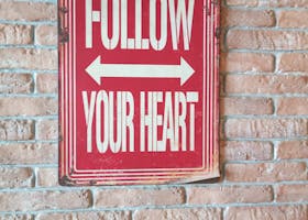 Red and white motivational sign on a vintage brick wall background.