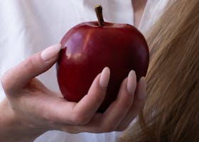 Close-up of a woman holding a red apple, symbolizing health, temptation, and nature.