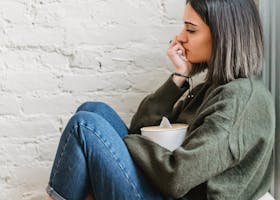 Young woman sitting in a pensive mood with tissues, expressing contemplation and emotion.