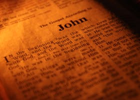 Focused close-up of the Bible's Gospel of John, highlighting sacred scriptures under warm light.