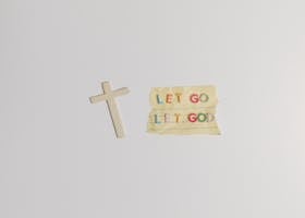 A simple and powerful image featuring a cross alongside the inspiring quote 'Let Go Let God' on paper.